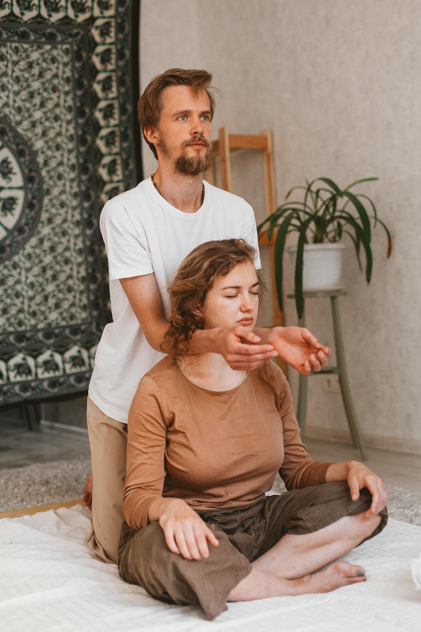 A man and woman engaging in a healing meditation session indoors, focusing on mindfulness.