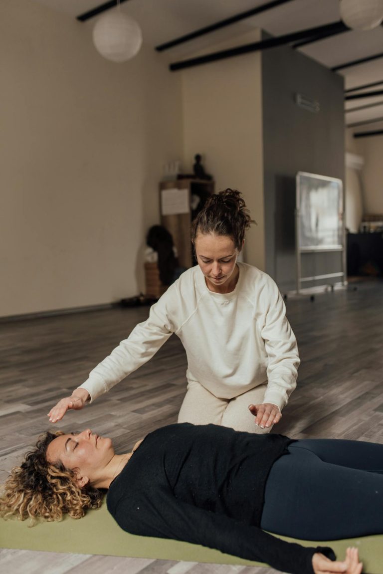 Two women in a serene yoga studio engage in a healing meditation session. Peaceful and focused.